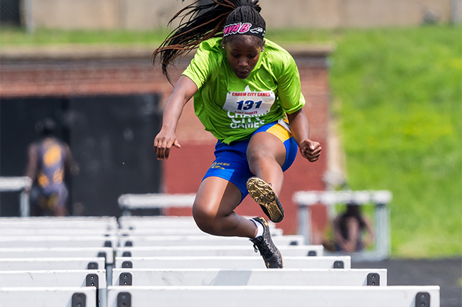 Woman jumping over barriers in track and field event